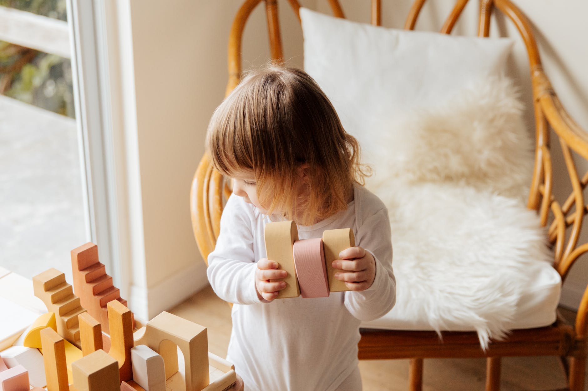 adorable kid playing with wooden construction blocks