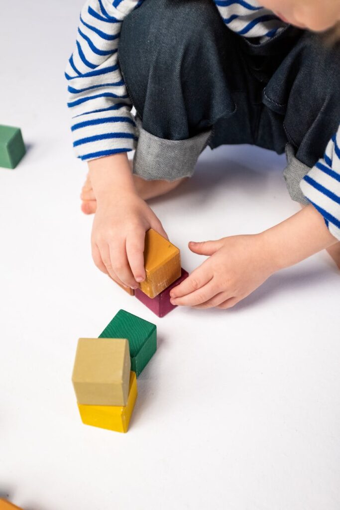 person in blue and white striped long sleeve shirt holding yellow and green blocks